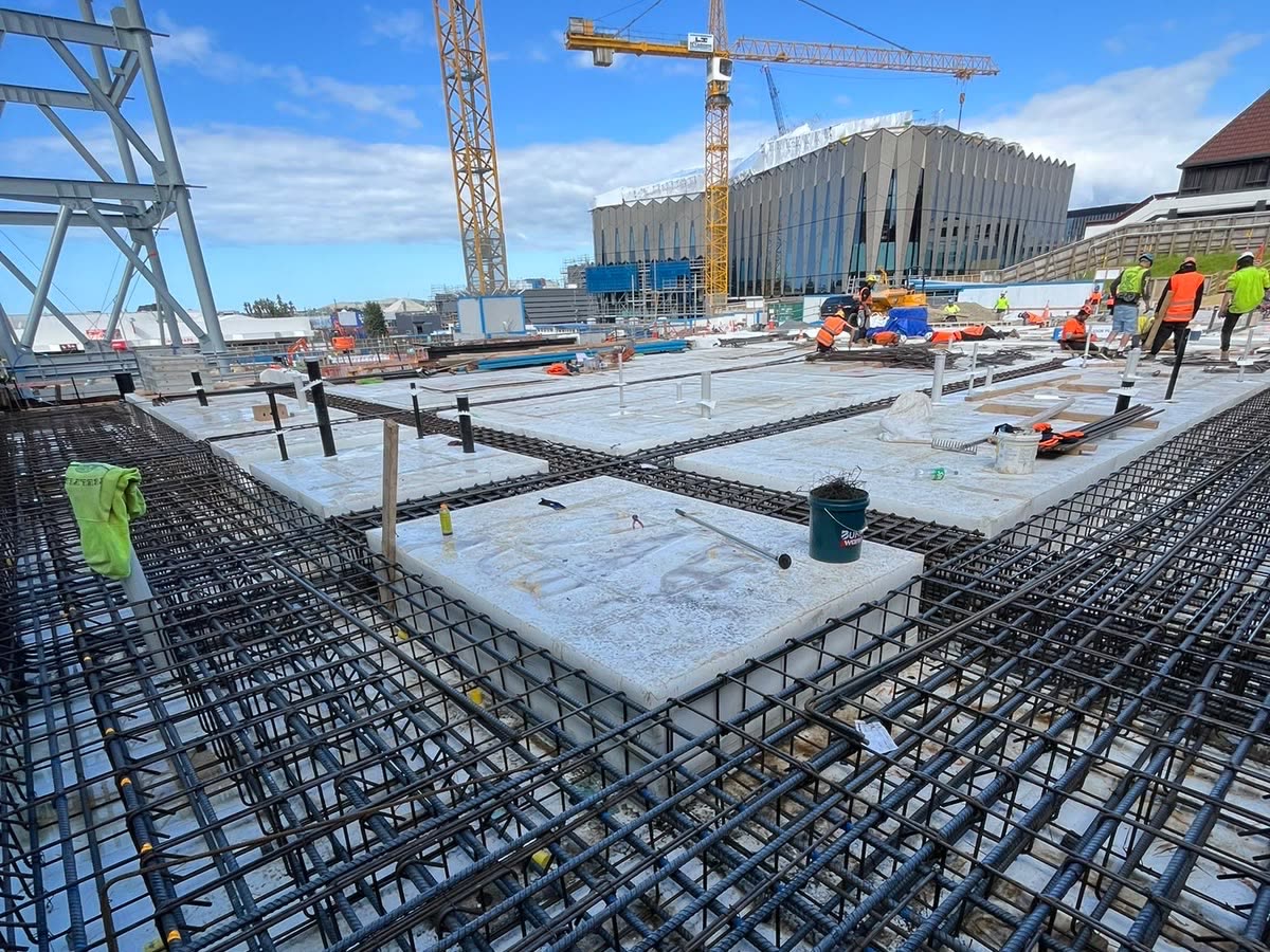 Beam cages and slab reinforcing on a commercial deck with tower cranes overhead
