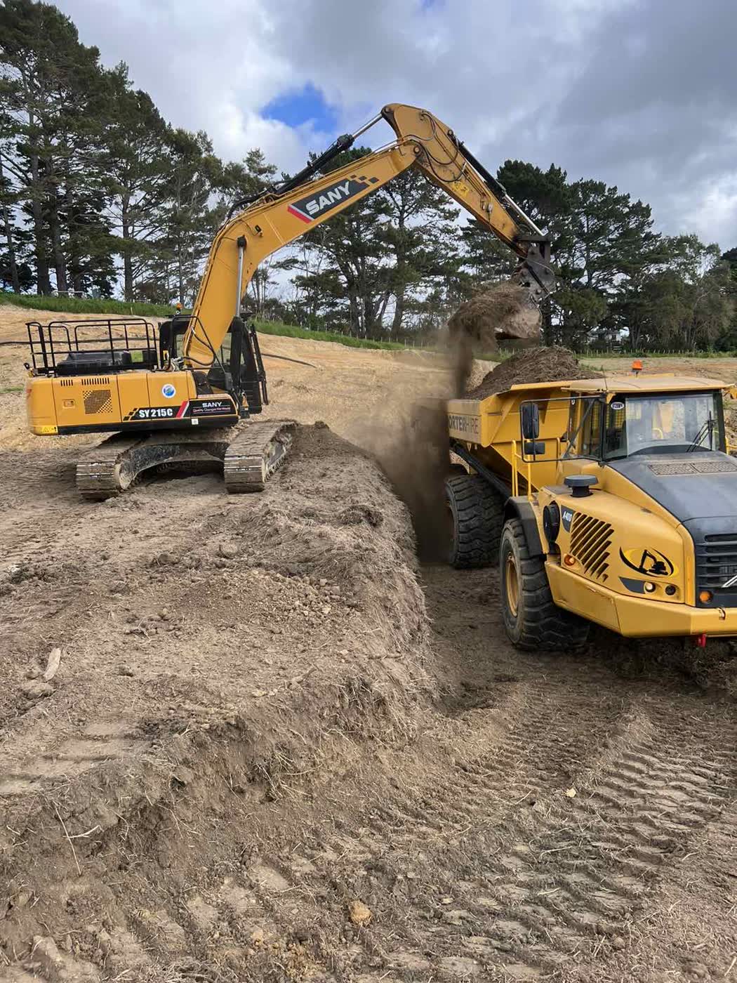 SANY excavator loading an articulated dump truck with earth