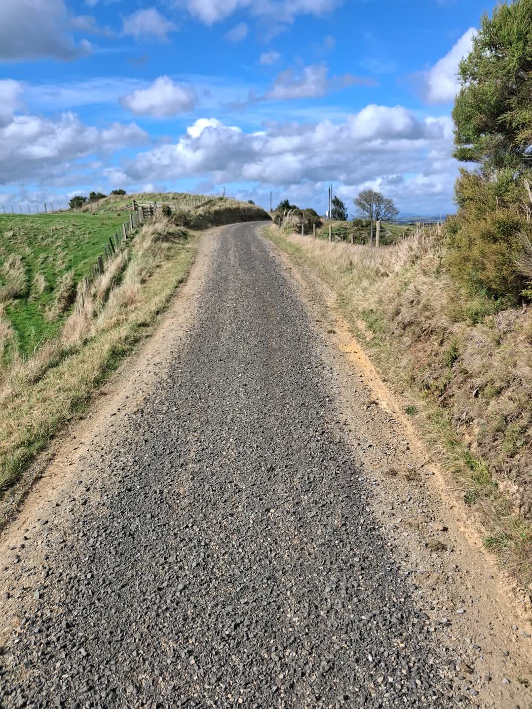 Freshly metalled gravel road running over a rural hill